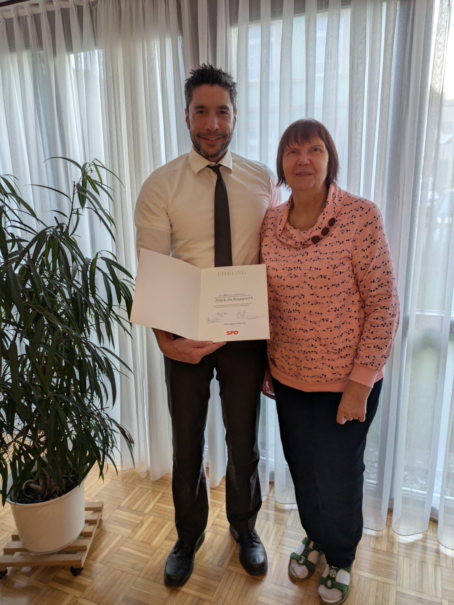 Die Ortsvorsitzende Hildegard Buchwitz-Schmidt überreicht Bürgermeister Nick Schuppert die Ehrenurkunde.